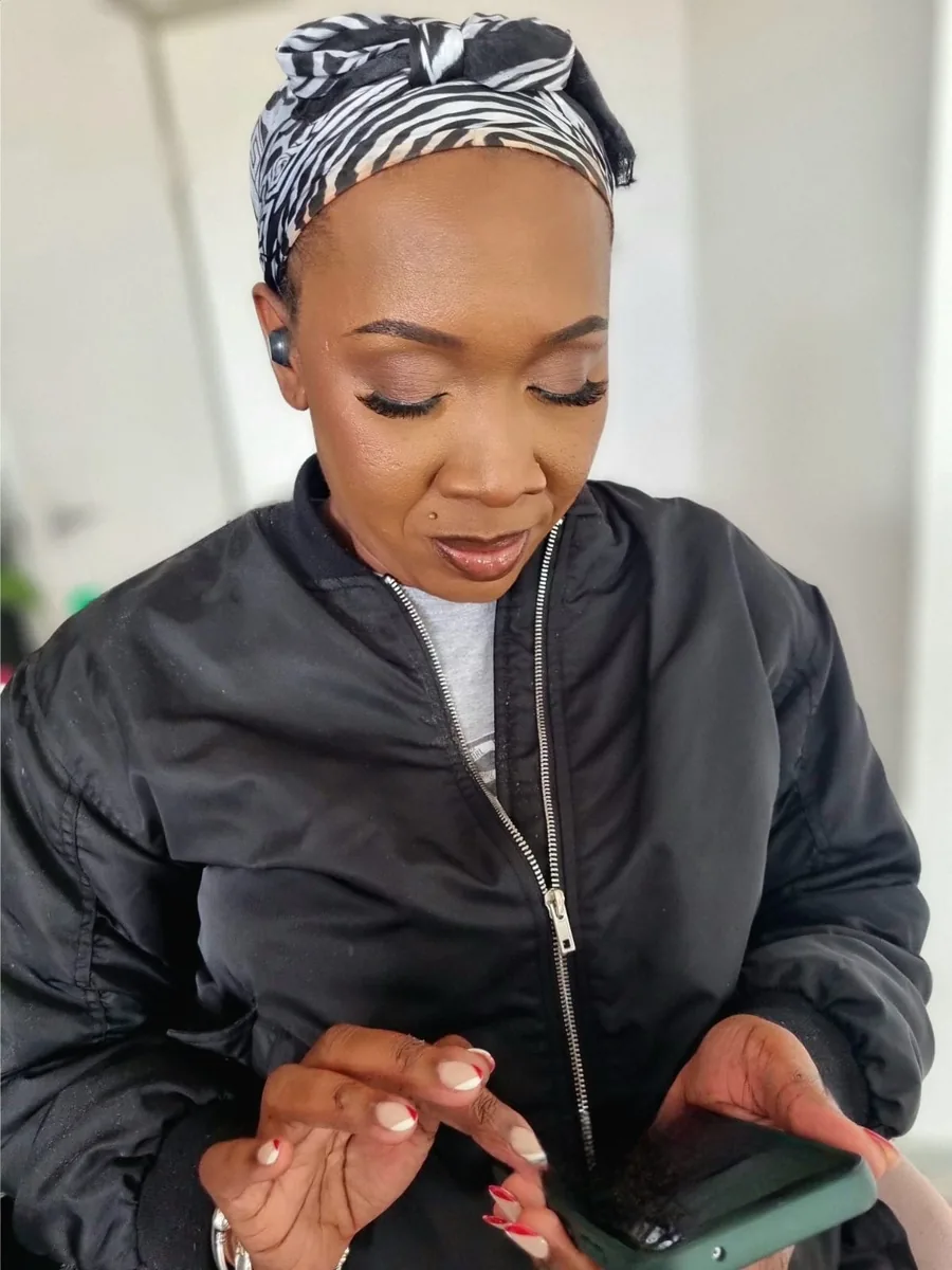 A client with a headwrap and neat make-up in the bright interior where the work is done