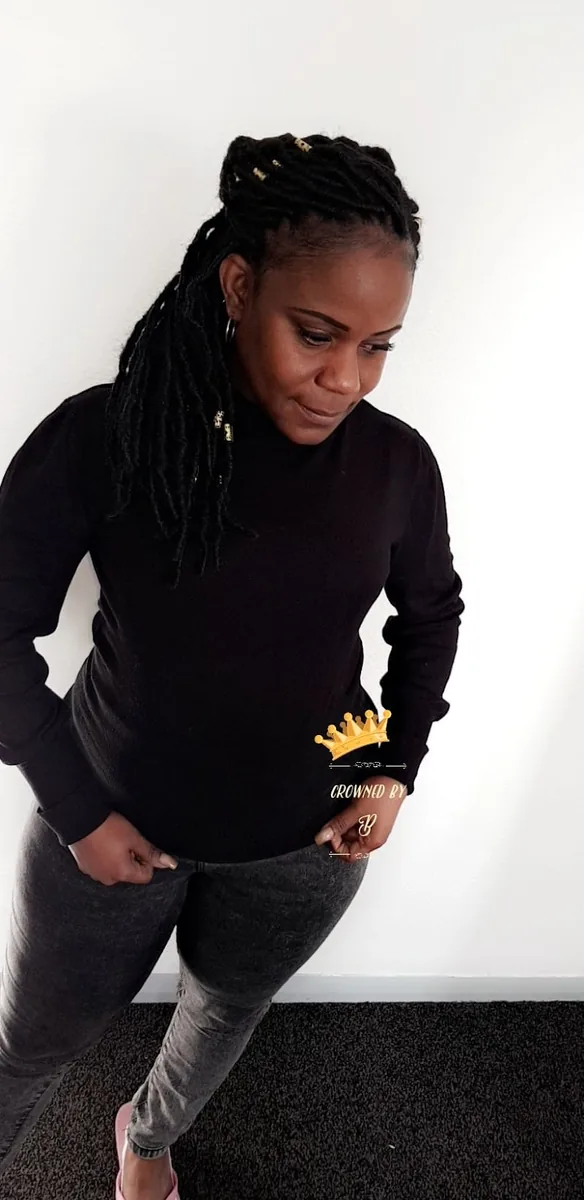 A client against a white wall showing long locs styled to one side