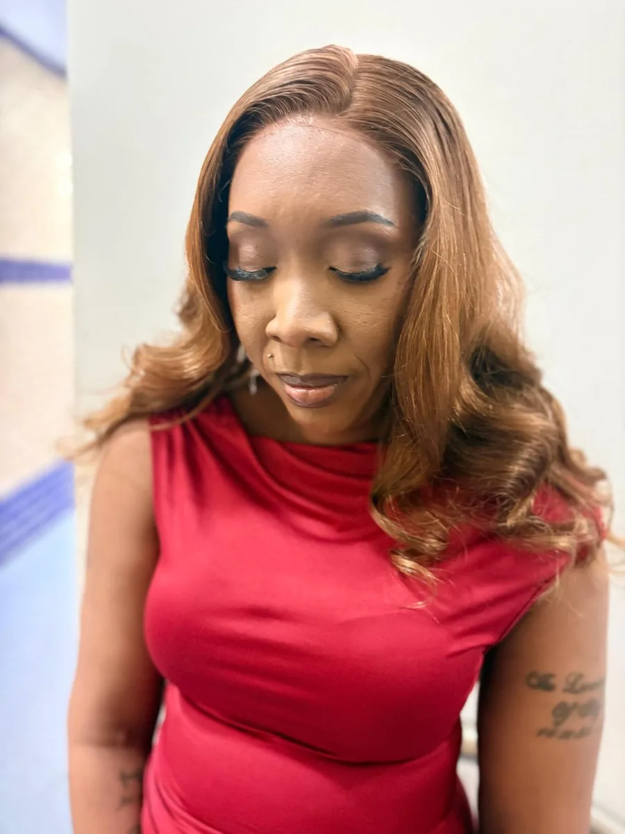 A client with long honey-blonde waved hair and finished make-up, looking down